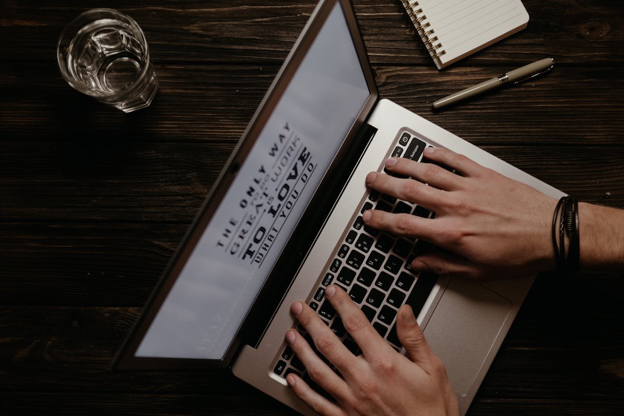Hands on a laptop with an inspirational quote displayed on the screen, shot from above.